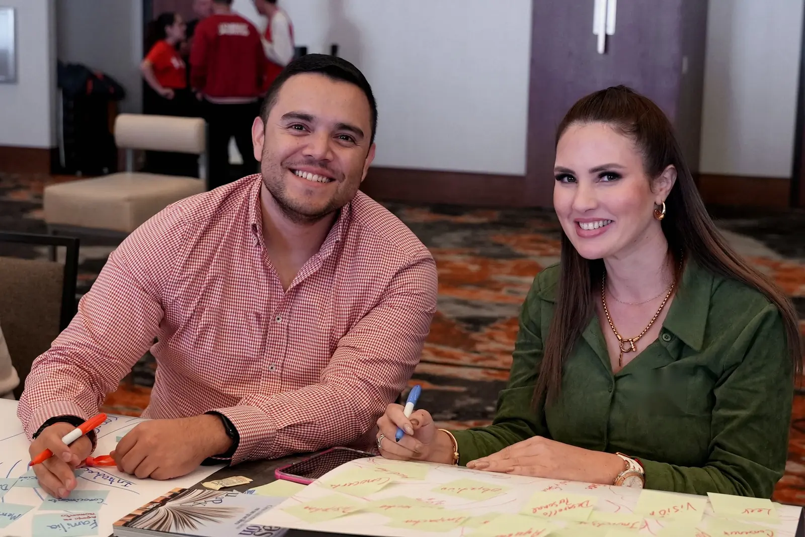 Dos integrantes del MAS sonríen en su mesa de trabajo llena de notas adhesivas