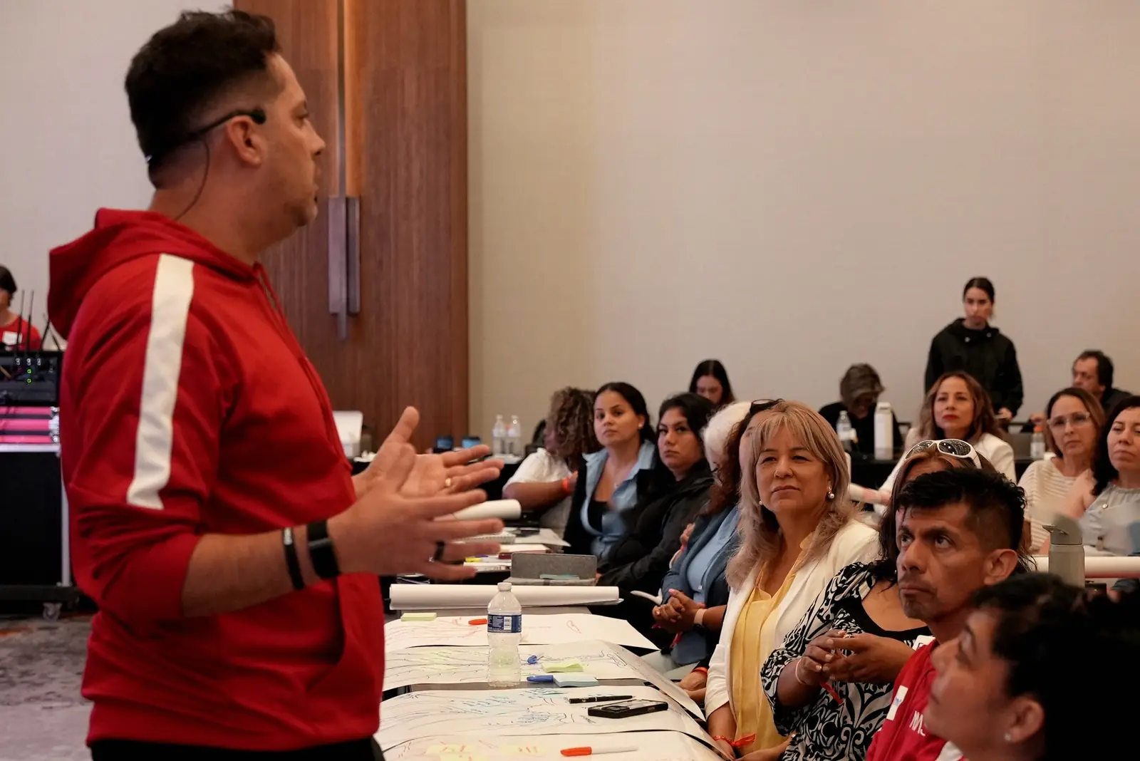 Jorge Serratos explica de pie junto a una mesa de trabajo con integrantes del MAS